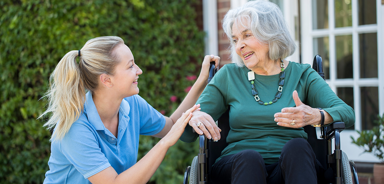 Image of nurse helping helderly person in a wheelchair.